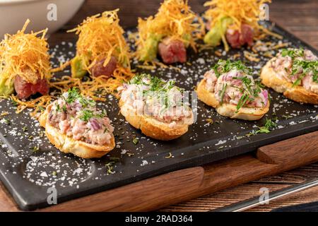 Bruschetta mit Meeresfrüchten mit asiatischen Aromen auf einem Steinschneidbrett Stockfoto