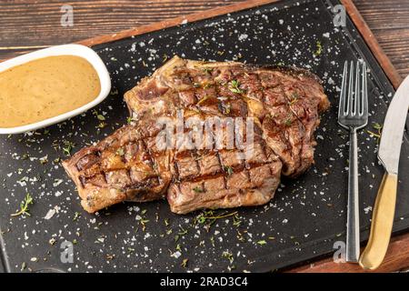 Gegrilltes Tomahawk-Steak auf einem Steinschneidebrett im Steakhouse-Restaurant Stockfoto