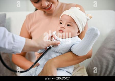 Nahaufnahme eines niedlichen Babys, das von einem Arzt mit einem Stethoskop untersucht wird. Kinderbetreuungskonzept. Neugeborenes, Kleinkind, Kind Stockfoto