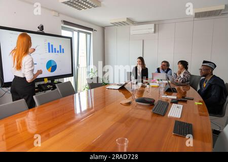 Eine Geschäftsfrau stellt ihren Kollegen während einer Konferenz Folien vor Stockfoto