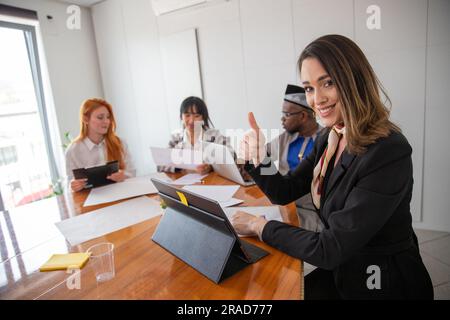 Eine Geschäftsfrau gibt während eines Geschäftstreffens die Daumen nach oben Stockfoto