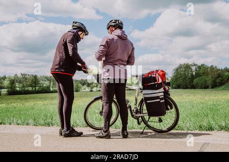Zwei Radfahrer sehen sich die Karte der Romantischen Straße an Stockfoto