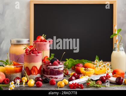Saubere Essensideen zum Frühstück oder Snack. Auswahl an Beerenobst-Smoothies, Säften und Chiasamen-Pudding vor einer Tafel. Konzept von Stockfoto