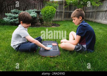 Zwei junge Jungs spielen ein Tic-tac-Toe-Spiel im Hinterhof zusammen. Stockfoto