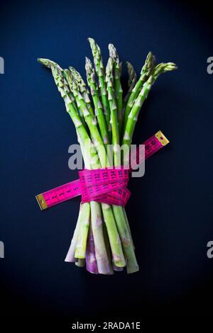 Ein Bündel grüner Spargel, gebunden mit einem pinkfarbenen Band Stockfoto