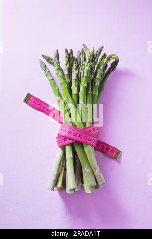 Ein Bündel grüner Spargel, gebunden mit einem pinkfarbenen Band Stockfoto