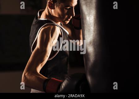 Nahaufnahme eines jungen Boxers, der während eines Trainings einen Boxsack schlägt. Stockfoto