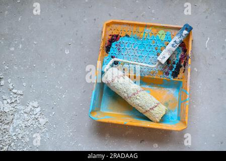 Komposition mit Farbe, Rolle, Schale, Farbmustern und Pinsel auf Betonhintergrund Stockfoto