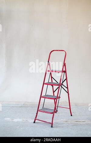 Red ladder against concrete wall of room interior under construction Stockfoto