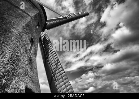 Dramatisches Schwarz-Weiß-Bild einer niederländischen Windmühle mit bewölktem Himmel Stockfoto