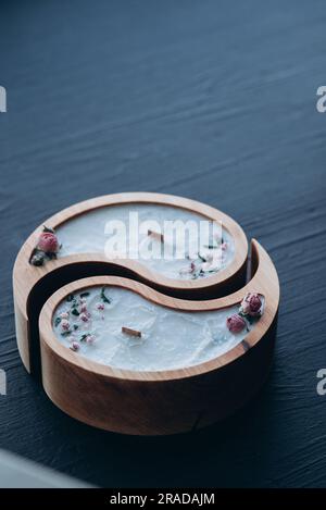 Handgefertigtes Aroma-Konzept. Sojakerze in Yin- und Yang-Form aus Holz und trockene Blumen mit natürlichem Wachsduft Stockfoto