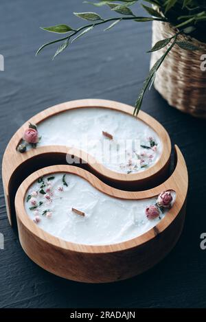 Handgefertigtes Aroma-Konzept. Sojakerze in Yin- und Yang-Form aus Holz und trockene Blumen mit natürlichem Wachsduft Stockfoto