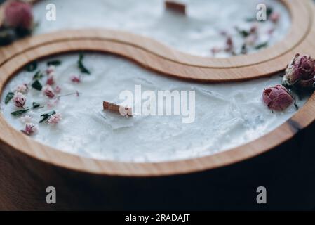 Handgefertigtes Aroma-Konzept. Sojakerze in Yin- und Yang-Form aus Holz und trockene Blumen mit natürlichem Wachsduft Stockfoto