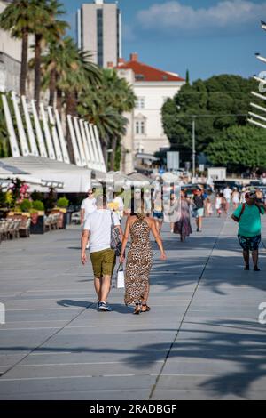 Ein Paar, das an einem warmen mediterranen Sommerabend entlang der Hauptstraße in Grad Split kroatien spaziert. Stockfoto