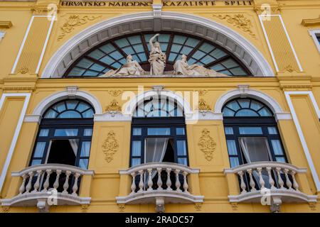 Bogenfenster auf einem hellgelb gestrichenen Nationaltheater in Grad Split, kroatien. Skulpturen und Statuen an der Vorderseite des kroatischen Nationaltheaters Stockfoto