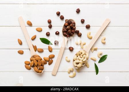 Sortiment an Muttern in Holzlöffel auf farbigem Tisch. Cashew, Haselnüsse, Walnüsse, Mandeln. Mischung aus Muttern Draufsicht und Kopierbereich. Stockfoto