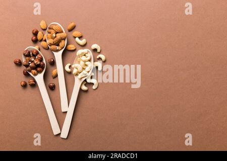 Sortiment an Muttern in Holzlöffel auf farbigem Tisch. Cashew, Haselnüsse, Walnüsse, Mandeln. Mischung aus Muttern Draufsicht und Kopierbereich. Stockfoto