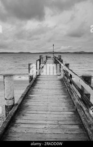 Ein hölzerner Pier in einem Sturm im Maraetai Harbour östlich von Auckland auf der neuseeländischen Nordinsel. Maraetai liegt an der Tāmaki-Straße im Hauraki-Golf. Stockfoto