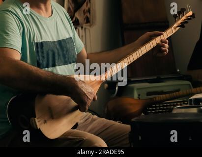 Ein Mann, der türkischen Musikinstrument-Baglama in einheimischen Klamotten spielt. Baglama ist das am häufigsten verwendete String-Volksinstrument in der Türkei Stockfoto