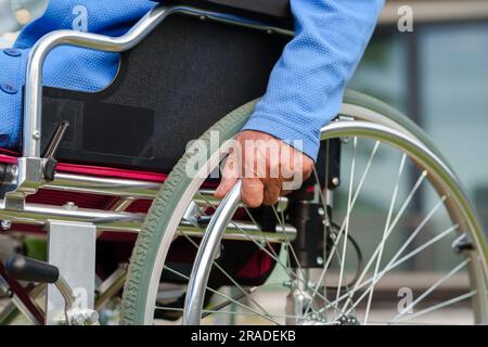 Nahhand einer behinderten Seniorin am Rollstuhlrad Stockfoto