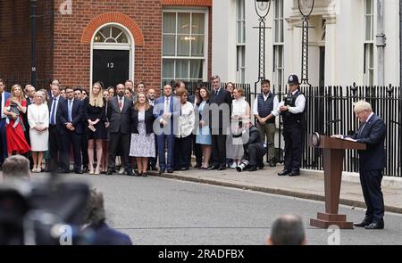 Ministerpräsident Boris Johnson, beobachtet von Frau Carrie Johnson (äußerste Linke hält Tochter Romy) und Charlotte Owen (erste Reihe 5. links), liest eine Erklärung vor der Downing Street 10, London, und tritt als Konservativen Parteiführer offiziell zurück, nachdem Minister und Abgeordnete deutlich gemacht hatten, dass seine Position unhaltbar ist. Er wird Premierminister bleiben, bis ein Nachfolger eingesetzt ist. Foto: Donnerstag, 7. Juli 2022. Stockfoto