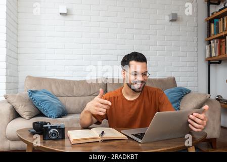 Ein junger, intelligenter Student, der zu Hause auf dem Boden sitzt und als freiberuflicher, entfernter Fremdsprachenprofessor arbeitet und den Leuten englisch beibringt Stockfoto