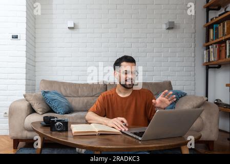 Ein junger, intelligenter Student, der zu Hause auf dem Boden sitzt und als freiberuflicher, entfernter Fremdsprachenprofessor arbeitet und den Leuten englisch beibringt Stockfoto