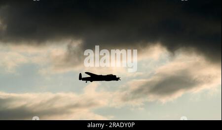 Flug im Battle of Britain Memorial, Lancaster-Flugzeug, über humberside, Großbritannien, Silhouette gegen dunkle Wolken Stockfoto