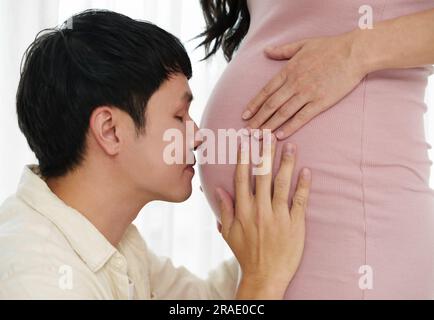 Ehemann küsst sich in den Bauch seiner schwangeren Frau Stockfoto