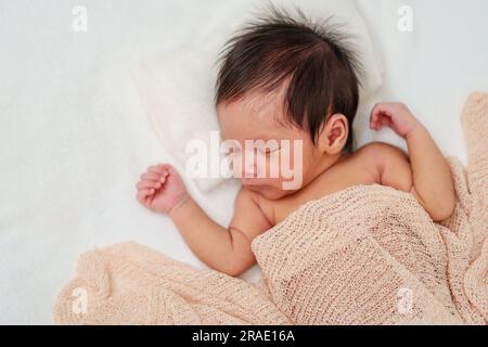 Neugeborenes, das in einer Decke auf einem Bett schläft Stockfoto