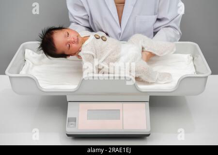 Neugeborenen-Gewichtsmessung auf der digitalen Waage mit Arzt im Krankenhaus Stockfoto