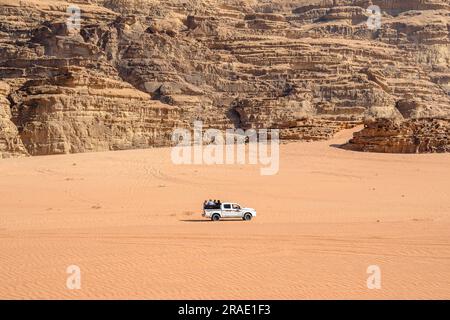 Wadi Rum, Jordanien - 19. Dezember 2022: Ein SUV mit Touristen fährt zwischen den Felsen auf dem Sand von Wadi Rum in Jordanien. Stockfoto