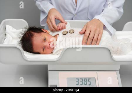 Neugeborenen-Gewichtsmessung auf der digitalen Waage mit Arzt im Krankenhaus Stockfoto