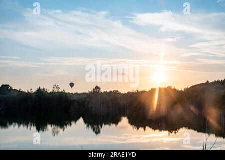 Erleben Sie die beeindruckende Schönheit der Natur, während eine atemberaubende Landschaft vor Ihren Augen enthüllt wird. Ein farbenfroher Sonnenuntergang bemalt den Himmel mit lebendigen Rot- und Goldtönen und wirft eine atemberaubende Reflexion über einen ruhigen Waldsee. Epische Wolken, geschmückt mit Rot- und Goldtönen, schaffen ein himmlisches Schauspiel, das die bezaubernde Landschaft ergänzt. Der ruhige See spiegelt die Pracht über uns wider und verstärkt das Gefühl von Staunen und Gelassenheit. Tauchen Sie ein in das majestätische Spektakel dieses pulsierenden Sonnenuntergangs, wo die Elemente der Natur zusammentreffen, um ein unvergessliches und fesselndes Erlebnis zu schaffen. Ma Stockfoto