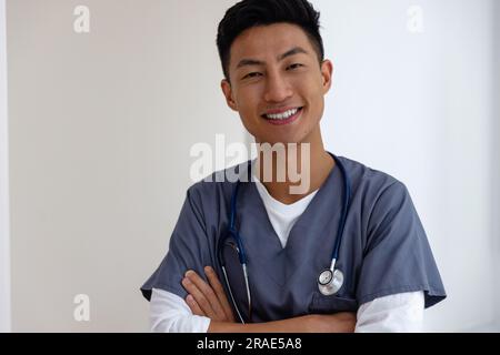 Porträt eines glücklichen asiatischen Arztes gegen die weiße Wand Stockfoto