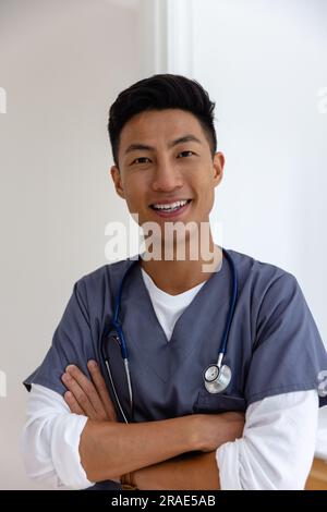 Porträt eines glücklichen asiatischen Arztes gegen die weiße Wand Stockfoto