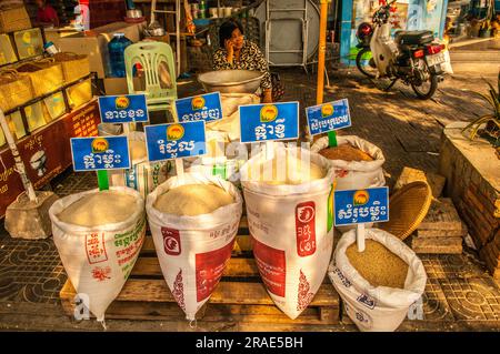 Eine kambodschanische Frau, die Reis auf einem lokalen Markt verkauft, spricht über ein Handy, Phnom Penh, Kambodscha. © Krai Stockfoto