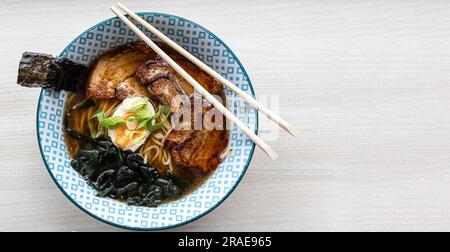 Asiatische Nudelsuppe Miso Ramen mit Scheiben von Chashu-geräuchertem Schweinefleisch, Nori-Algen und Frühlingszwiebeln. Draufsicht mit Platz für Text Stockfoto