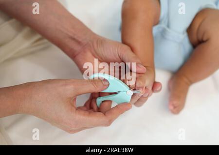 Mutter schneidet neugeborene Fingernägel am Fuß mit einer Nagelschere. Stockfoto