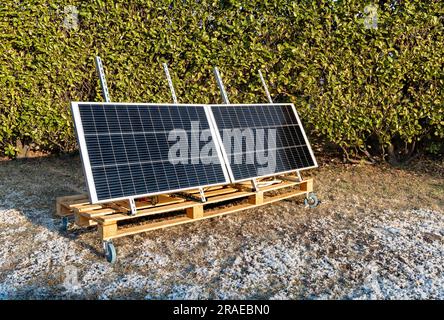 Photovoltaikpaneele auf der Holzpalette im Hausgarten zur Winterzeit. Konzept der grünen Energie. Stockfoto