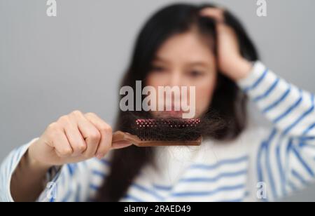 Gestresste Frau mit Haarausfall-Problem mit ihrer Haarbürste Stockfoto