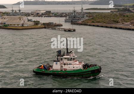 Cobh, Irland, EU. 9. Juni 2023 Alex, ein begleitender Schlepper im Hafen von Cobh mit einem Hintergrund von Haulbowline Island und der Marine. Servicebasis. Stockfoto