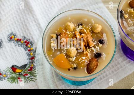 Traditionelles türkisches Dessert Asure, Noah's Pudding in stilvollen Glasschüsseln auf Holztisch Stockfoto