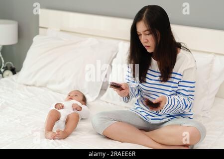 Gestresste Mutter mit Haarausfall nach der Geburt mit ihrem Baby zu Hause Stockfoto