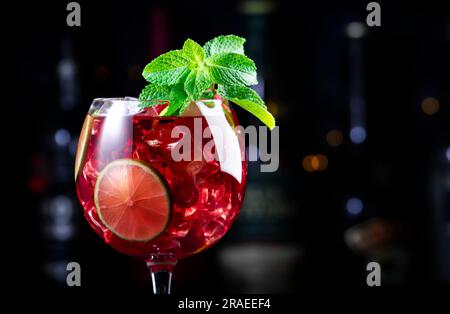 Alkoholische Cocktailgetränke aus königlicher Limonade mit Tequila, trockenem Gin, weißem Rum, Wodka, Likör, Limette, Himbeeren und Eis in Weinglas. Schwarzer Bartresen Ba Stockfoto
