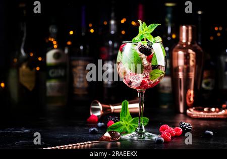 Mojito sangria alkoholisches Cocktailgetränk mit weißem Rum, Prosecco oder Sekt, Limettensaft, Himbeere, Heidelbeere, Brombeere und Eis im Weinglas Stockfoto