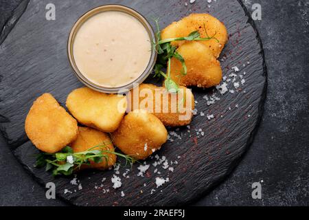 Gebratene Nuggets mit Soße und Kräutern auf einem schwarzen Stein. Draufsicht Stockfoto