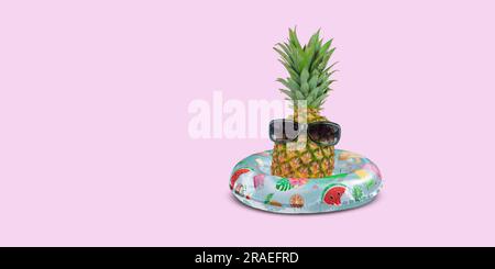 Ananas mit Sonnenbrille im aufblasbaren Schwimmring auf pinkfarbenem Hintergrund. Stockfoto