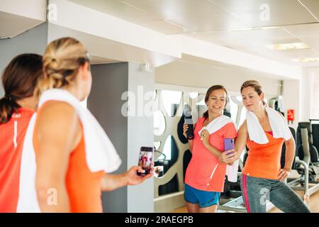 Zwei Mädchen machen Selfie mit Smartphone im Fitnessstudio Stockfoto