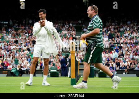 Novak Djokovic inspiziert die Feuchtigkeit auf dem Platz und applaudiert dem Bodenpersonal, das Laubblasgeräte herausschickt, um während einer Verzögerung bei Regen das Gras zu trocknen, während das Spiel am ersten Tag der Wimbledon Championships 2023 im All England Lawn Tennis and Croquet Club in Wimbledon stattfindet. Foto: Montag, 3. Juli 2023. Stockfoto